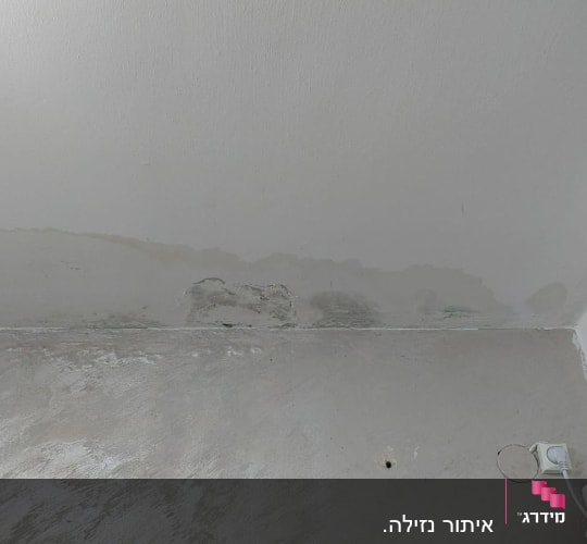 כתם רטיבות על קיר ליד שקע חשמל